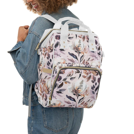 Floral diaper bag backpack with stylish pink design worn by woman in denim jacket, perfect for baby essentials and new moms.