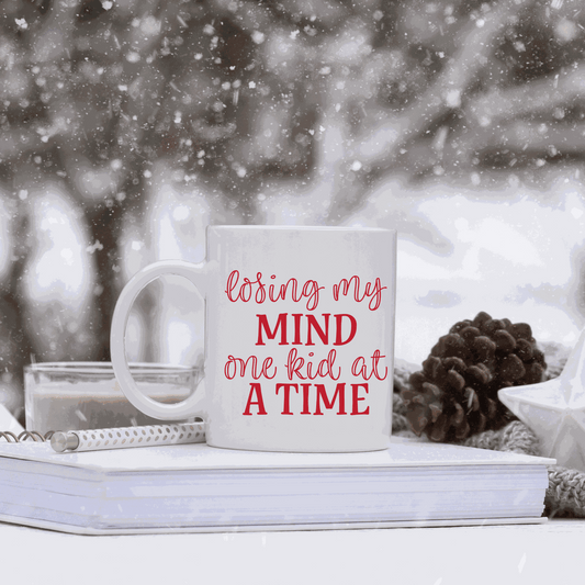 White ceramic mug with humorous "Losing my Mind one Kid at a Time" design.