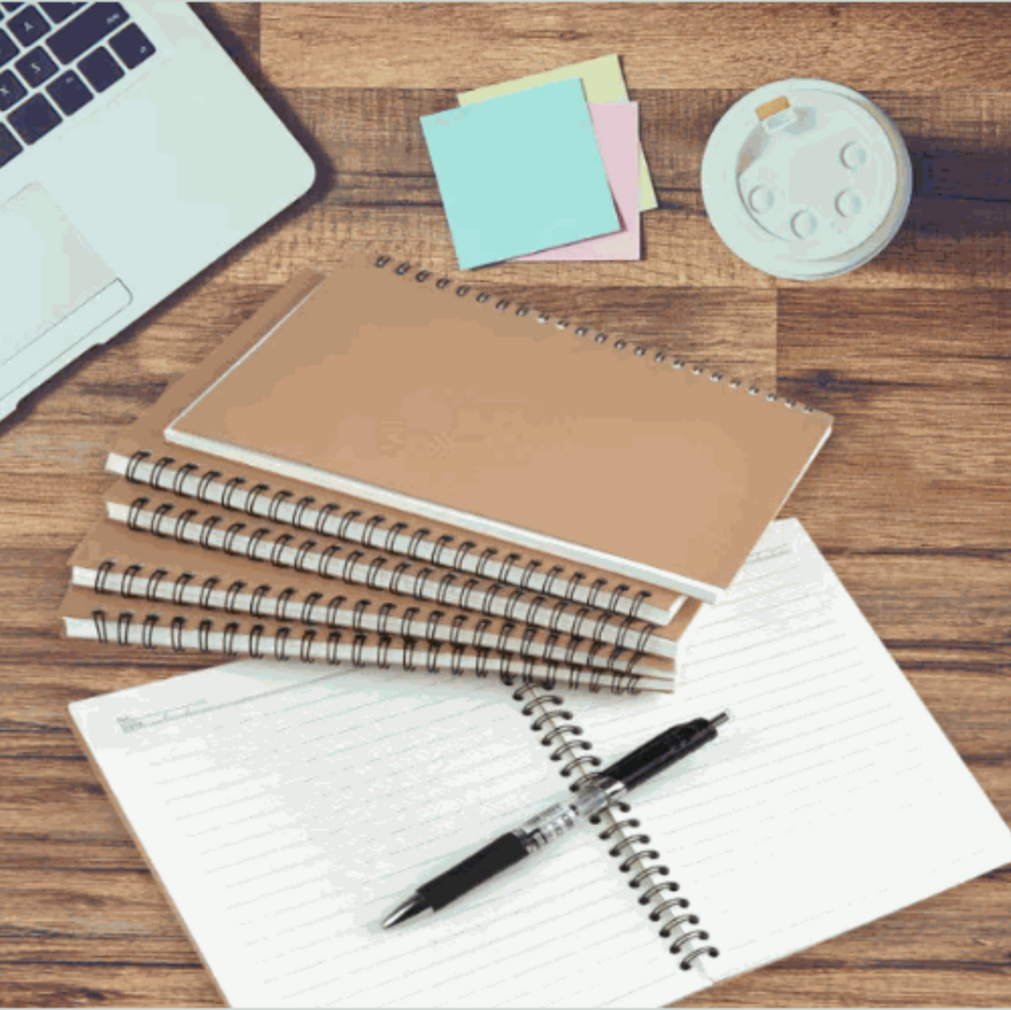 Personalized soft cover spiral notebooks on wooden desk with pen and sticky notes.