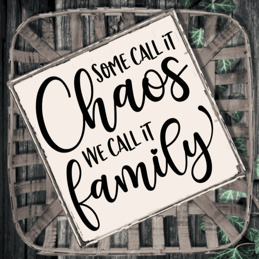 Handmade wood sign with "Some Call it Chaos, We Call it Family" phrase in black lettering on a white background.