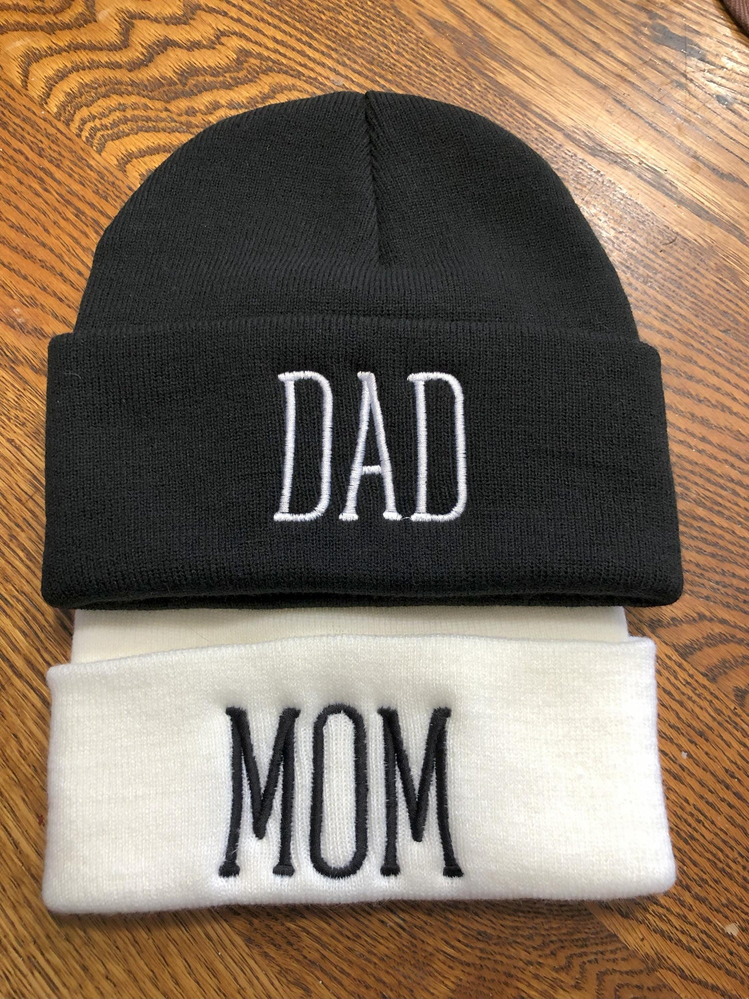 embroidered beanies in white and black with names 'Mom' and 'Dad'