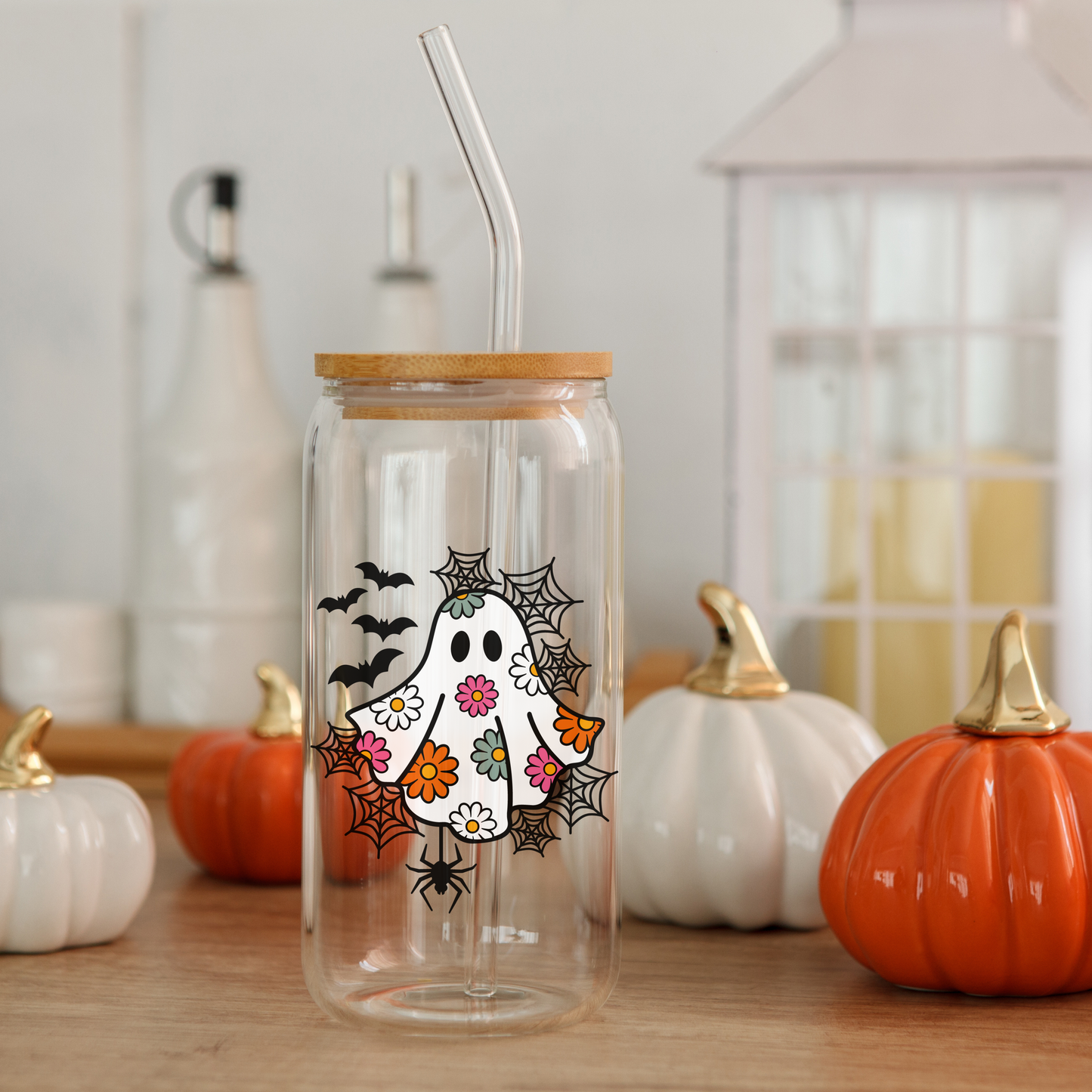 Halloween Daisy Ghost Glass Can Cup with bamboo lid and straw, surrounded by pumpkins.
