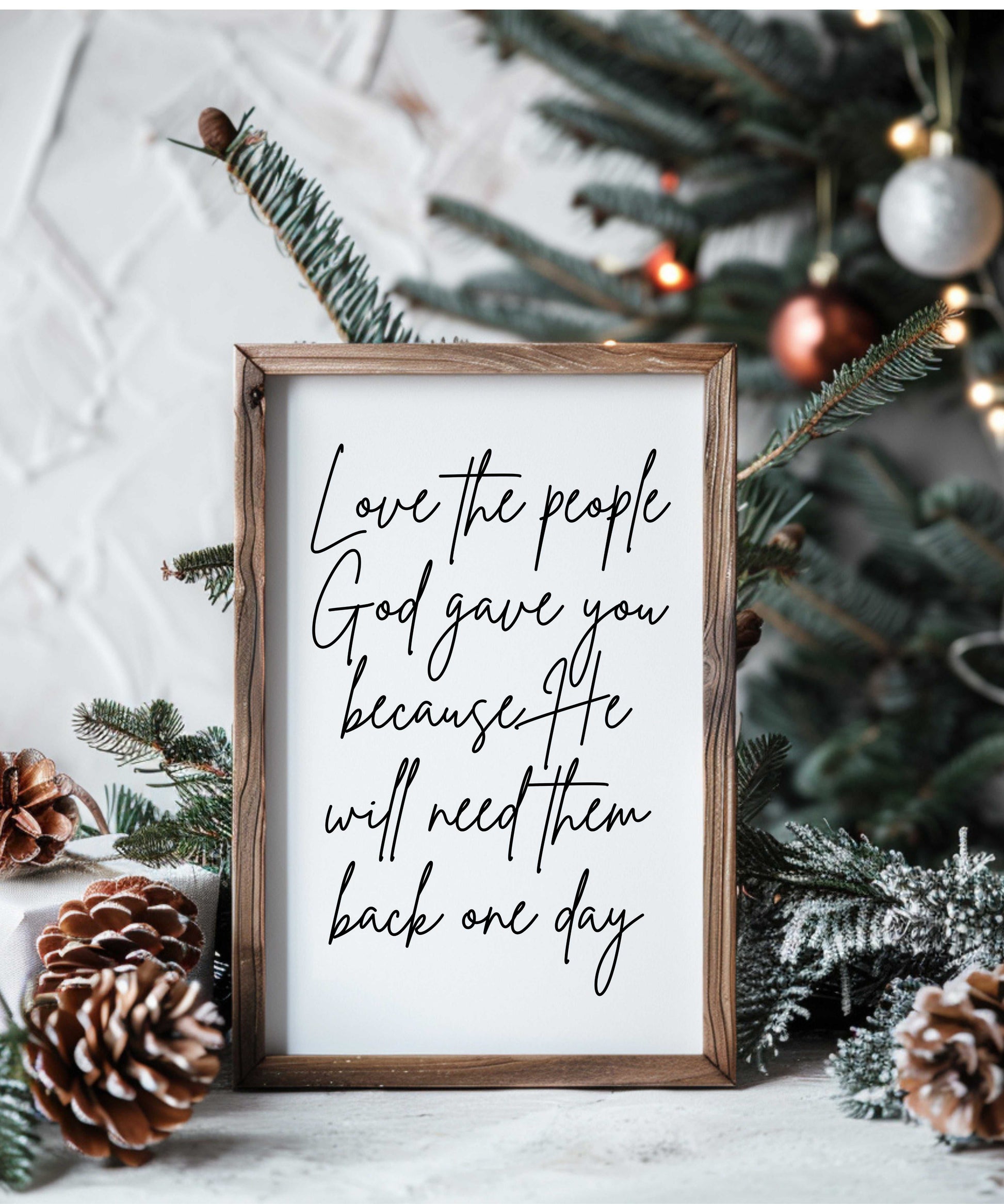 Handcrafted farmhouse wood sign with "Love the people God gave you" script in rustic frame, displayed with pinecones and Christmas decor