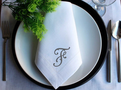 Monogrammed white linen wedding napkin with embroidered initial on plate setting