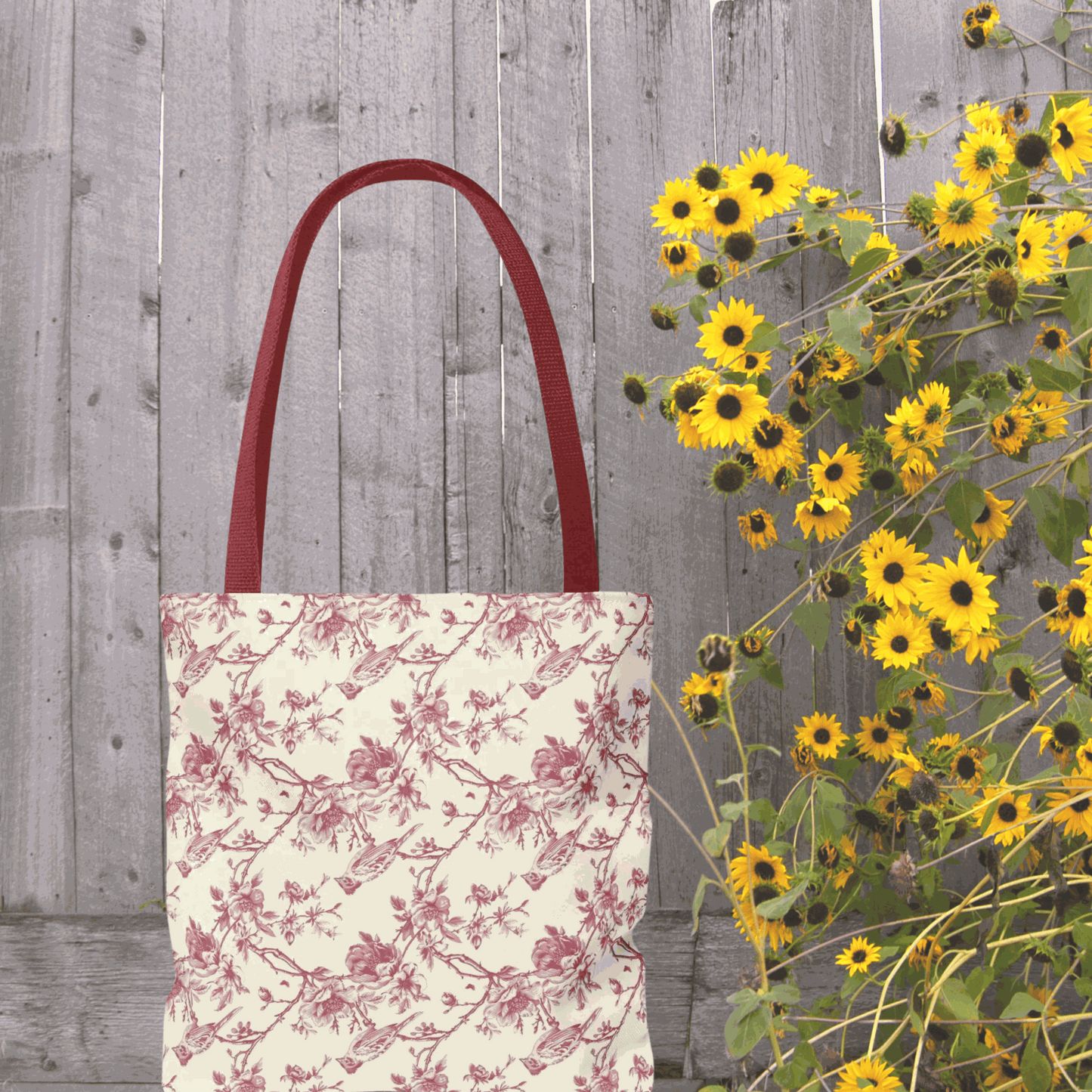 Pink Toile Tote Bag with flower print, reusable canvas, stylish and multi-purpose, next to vibrant yellow flowers.