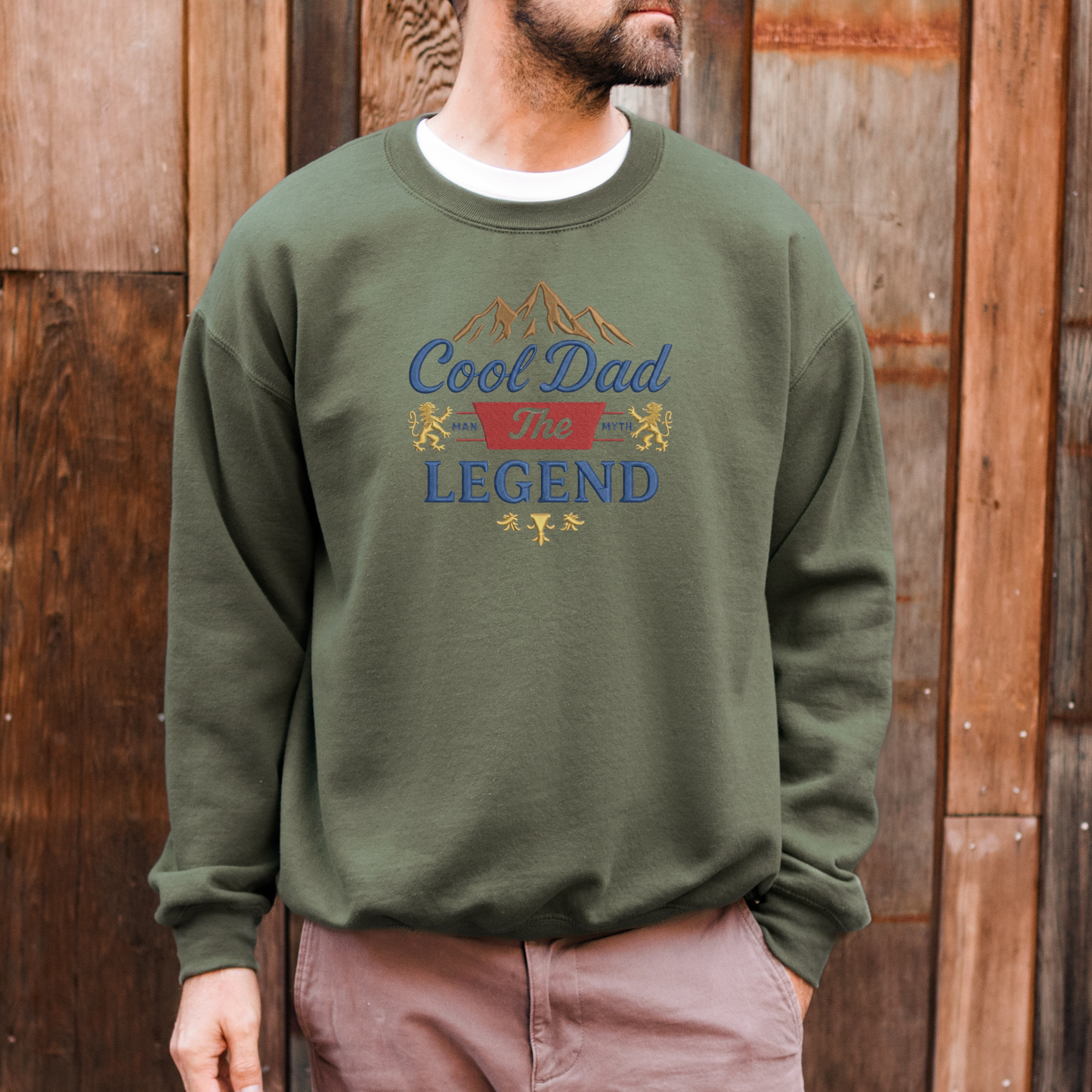 Person wearing a green sweatshirt with 'Cool Dad The Legend' text and graphics against a wooden background