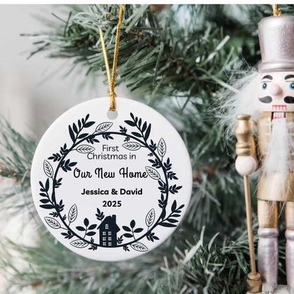 Personalized ceramic Christmas ornament for first holiday in new home with names Jessica & David 2025 hanging on tree with nutcracker nearby
