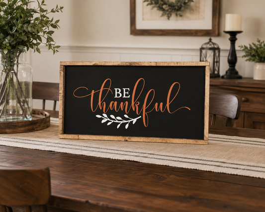 Decorative sign with 'Be Thankful' text on a table in a home setting