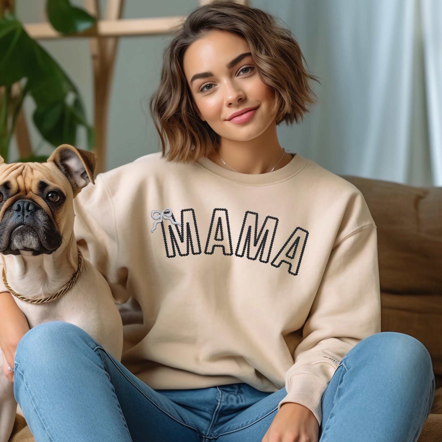Custom embroidered "MAMA" sweatshirt with personalized text and embroidered bow detail, worn by woman sitting with