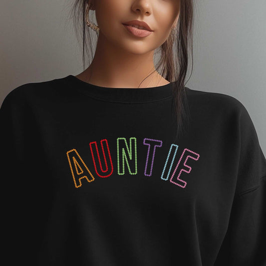 Black sweatshirt with rainbow embroidered "AUNTIE" lettering on front, worn by woman