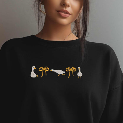 Olive green embroidered sweatshirt with geese and orange bows, cozy cotton blend.