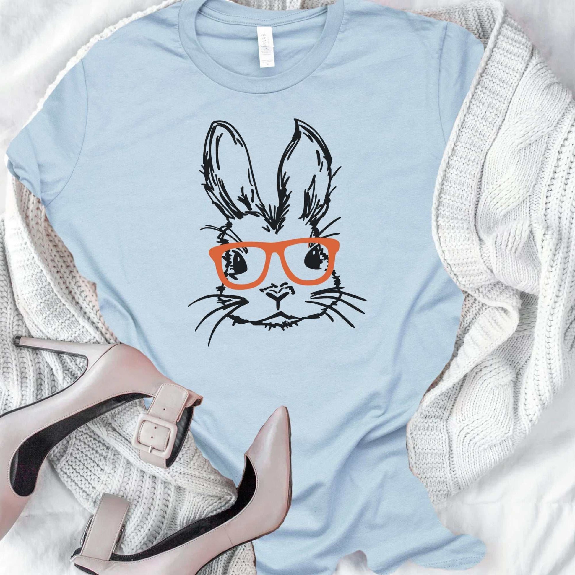 Adorable unisex Easter Bunny with glasses graphic tee in pastel blue, perfect for spring celebrations.