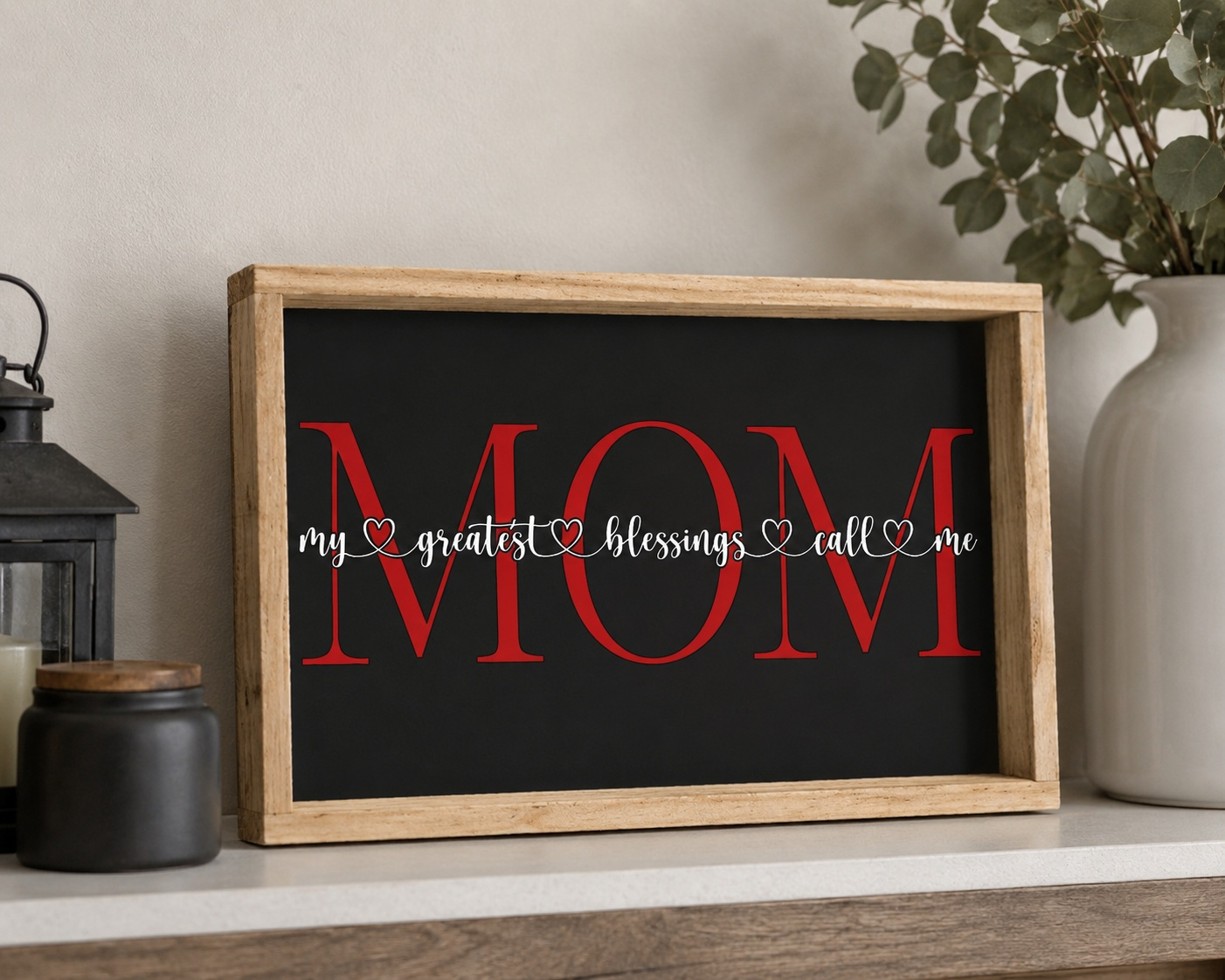 Decorative sign with 'MOM' and text in a wooden frame on a shelf.