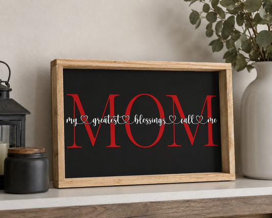 Decorative sign with 'MOM' and text in a wooden frame on a shelf.