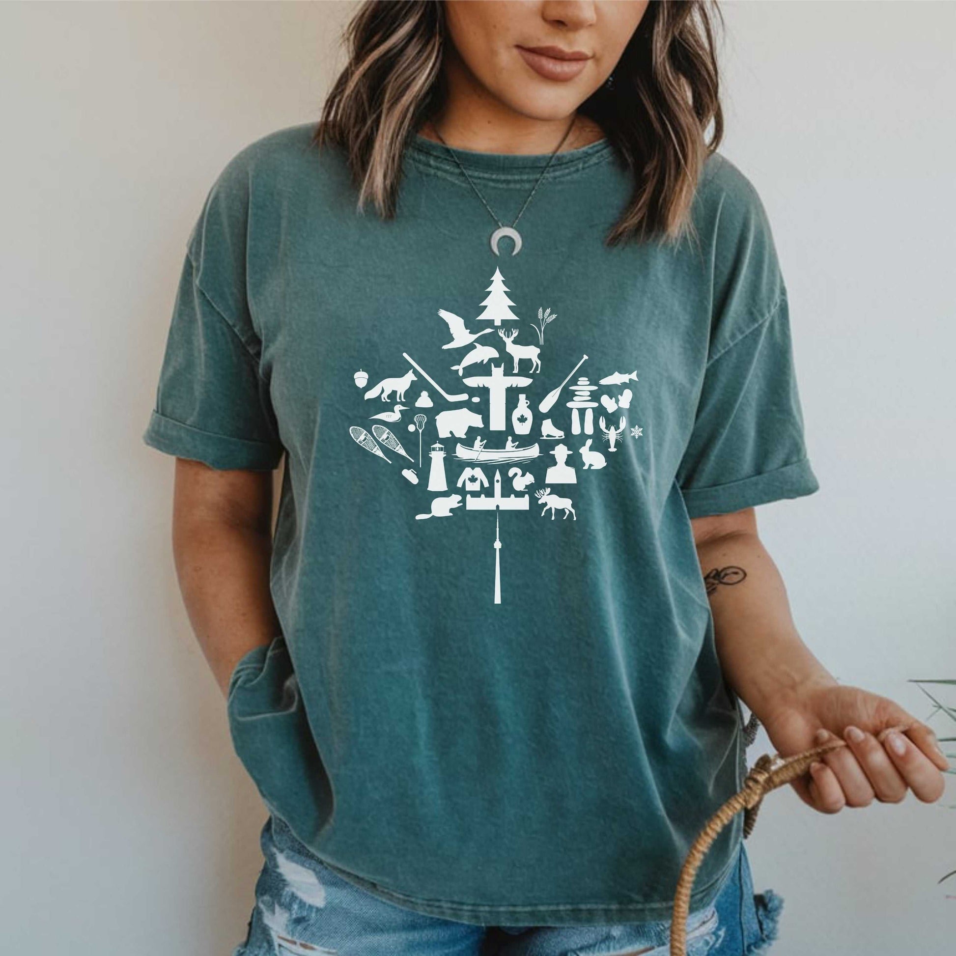 Unisex garment-dyed T-shirt featuring a red maple leaf design with iconic Canadian imagery.