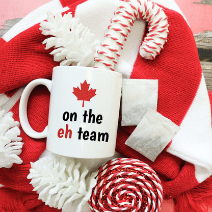 White ceramic mug with red maple leaf and "on the eh team" text, Canadian pride design, 11oz or 15oz size