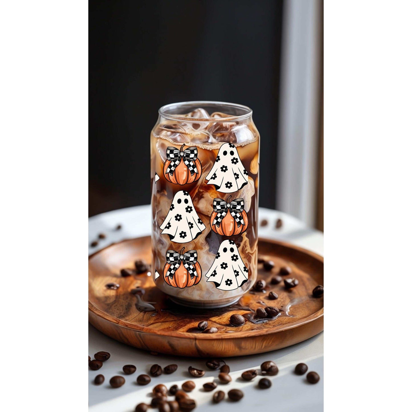 Halloween ghost and pumpkin-themed glass tumbler with bamboo lid and straw on a wooden tray.