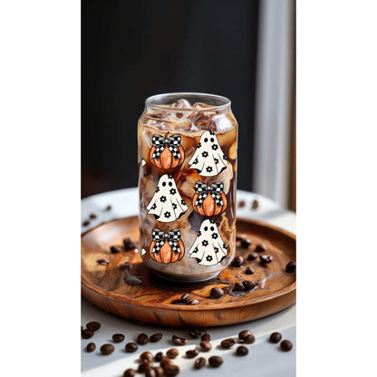 Halloween ghost and pumpkin-themed glass tumbler with bamboo lid and straw on a wooden tray.