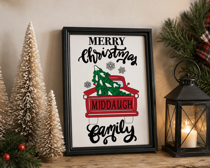 Framed Christmas sign with red truck and family name, surrounded by festive decor.