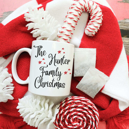 Custom Name Christmas Mug with The Hunter Family text on white enamel mug surrounded by red and white holiday decorations