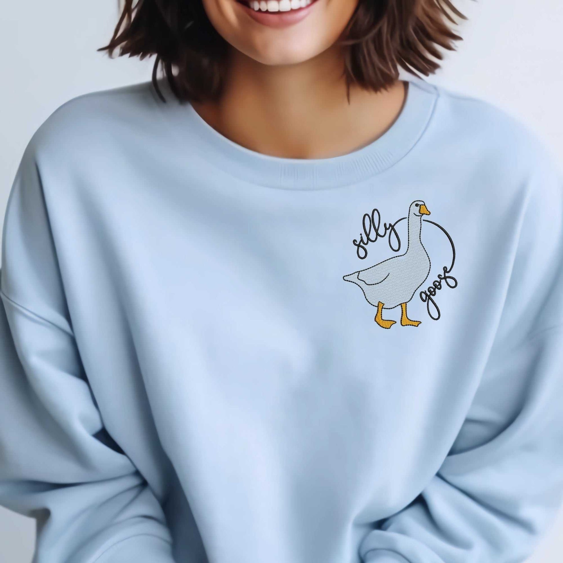 Silly Goose embroidered sweatshirt in soft pink featuring a charming goose design and "silly goose" phrase, crafted on a premium cotton/polyester blend for a cozy, playful look.