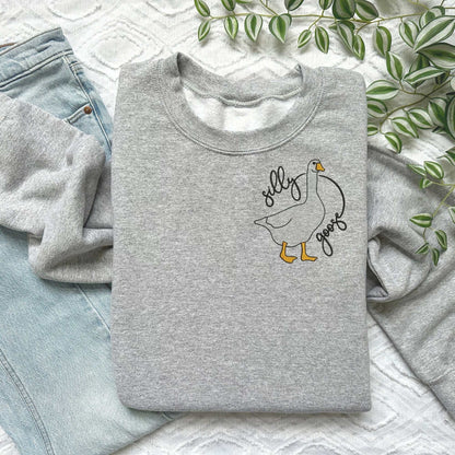 Silly Goose embroidered sweatshirt with goose design on pink crewneck, soft cotton/polyester blend, unisex fit.