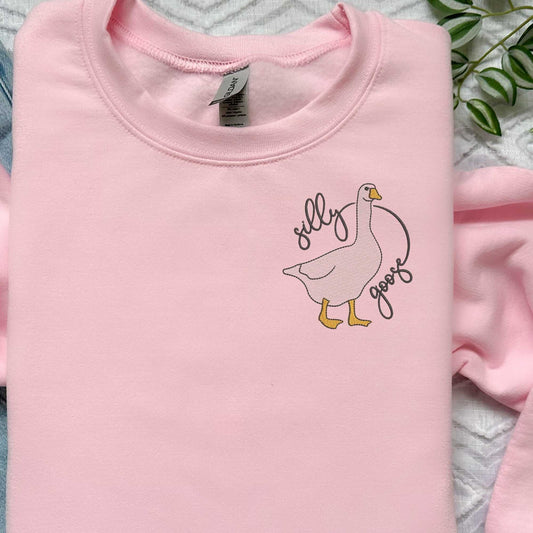 Pink embroidered sweatshirt with "Silly Goose" design; unisex fit, cotton/polyester blend.