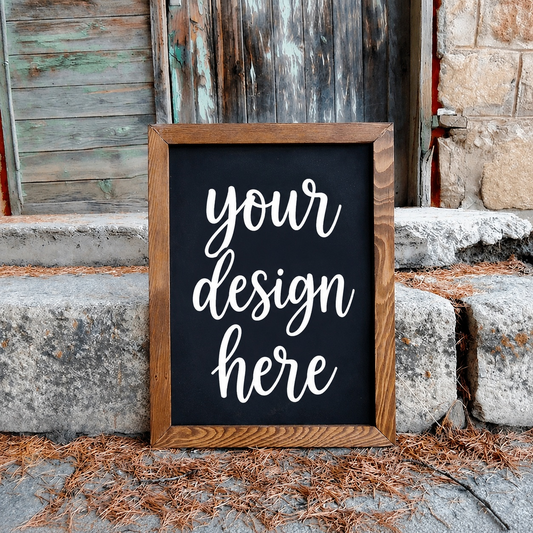 Black chalkboard with 'your design here' text in a wooden frame against a rustic stone wall.