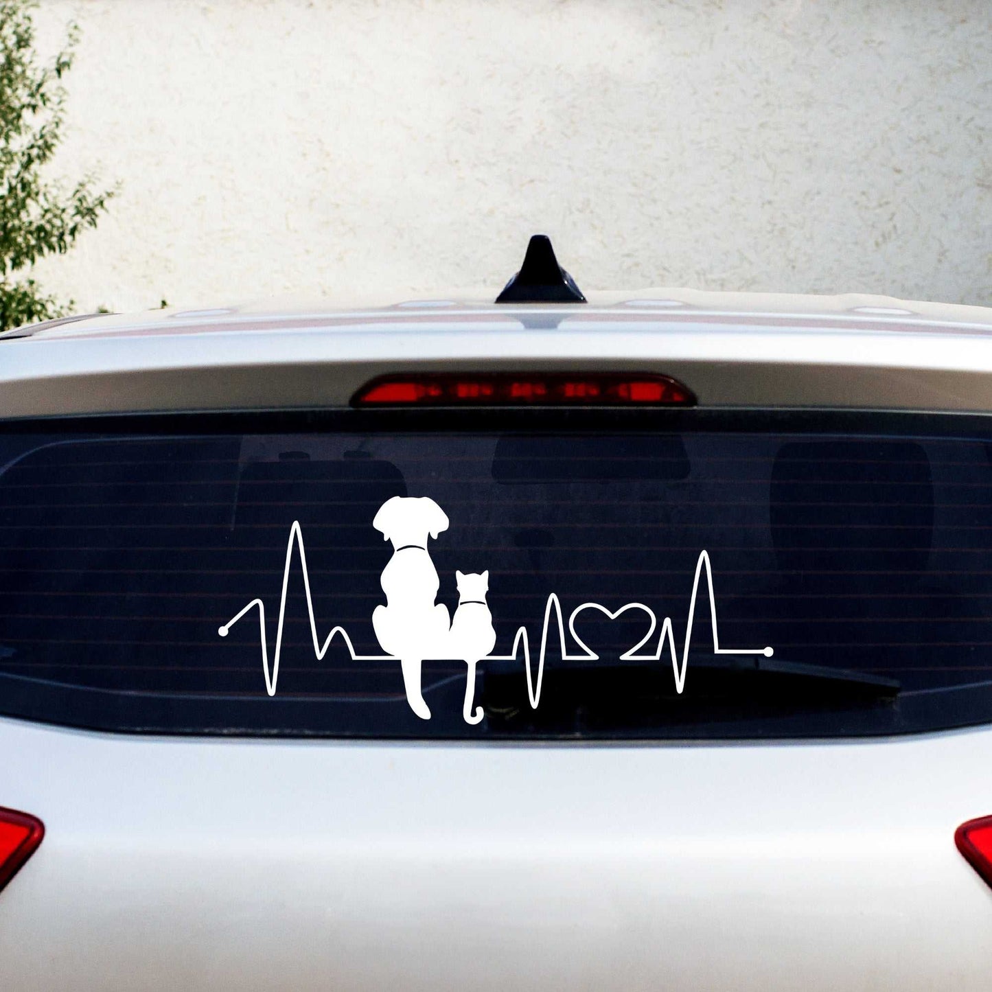 Dog and cat heartbeat car decal on rear window with pets silhouette and heart symbol in white vinyl.