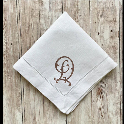 White napkin with brown monogram on a wooden surface