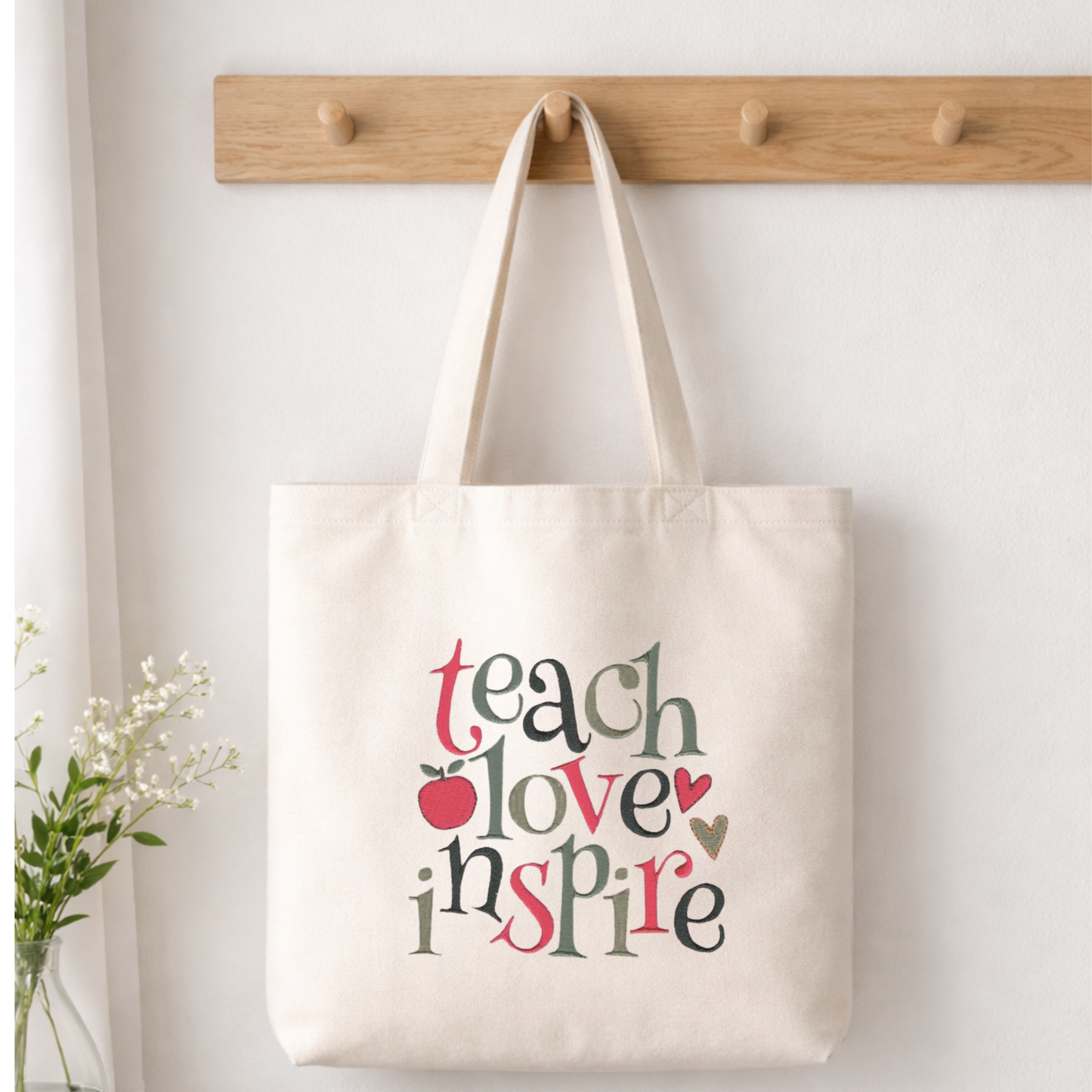 White canvas tote bag embroidered with the words Teach, Love, Inspire, perfect for educators and mentors.