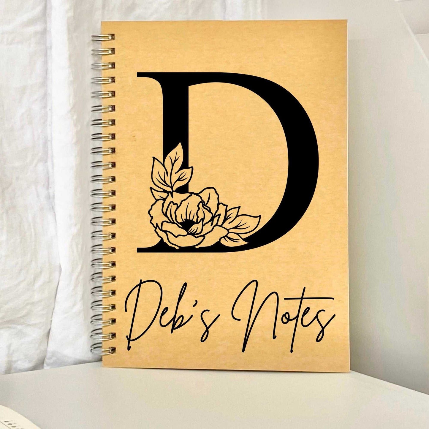 Unique monogrammed notebook with floral design, custom initial and name, kraft paper cover.