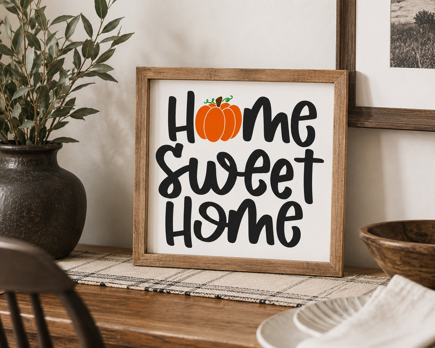 Framed sign with 'Home Sweet Home' and a pumpkin on a wooden surface.