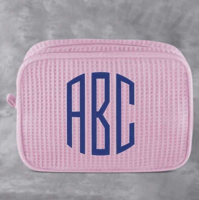 Monogrammed cosmetic bag with waffle texture and zipped compartments for makeup storage
