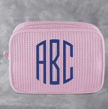 Monogrammed cosmetic bag with waffle texture and zipped compartments for makeup storage
