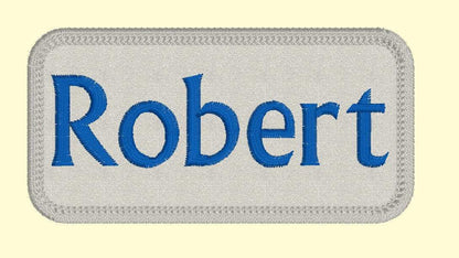 2" x 3" custom embroidered name patch with blue text "Robert" on a grey background for jackets.