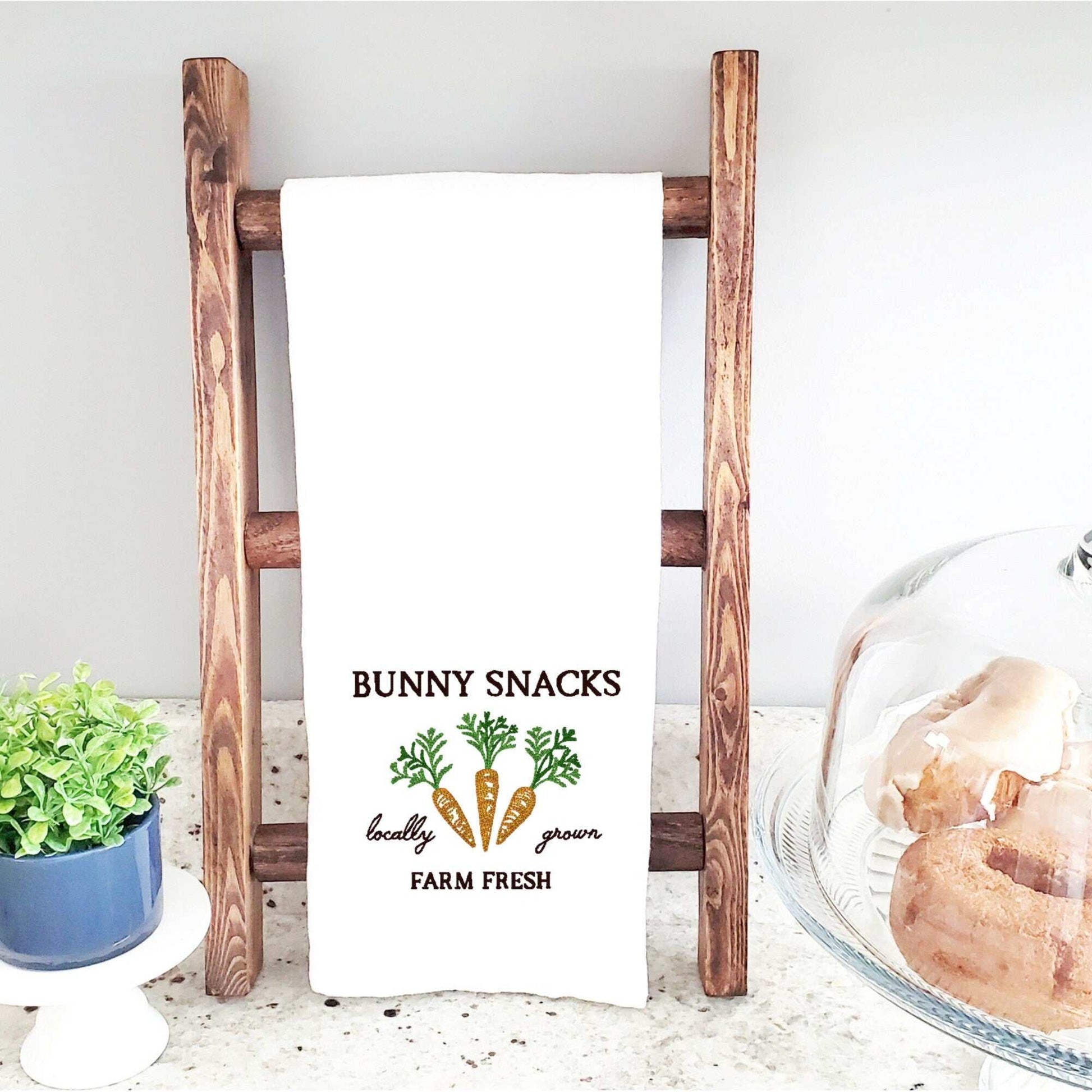 Easter-themed bunny snacks cotton tea towel with carrot embroidery on a wooden rack, 19"x28".