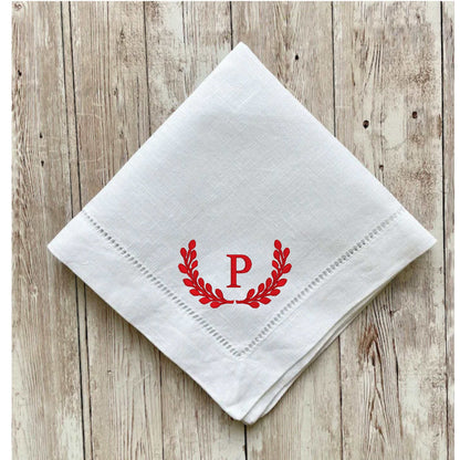 White linen blend dinner napkin with red embroidered initial P and classic hemstitch on wooden background