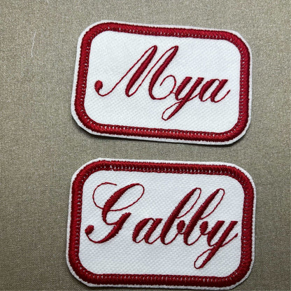 Custom embroidered name patches for jackets with red border and personalized text.