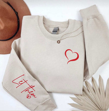 Embroidered cozy sweatshirt with heart detail and "Let Them" message on sleeve, ideal for emotional wellness.
