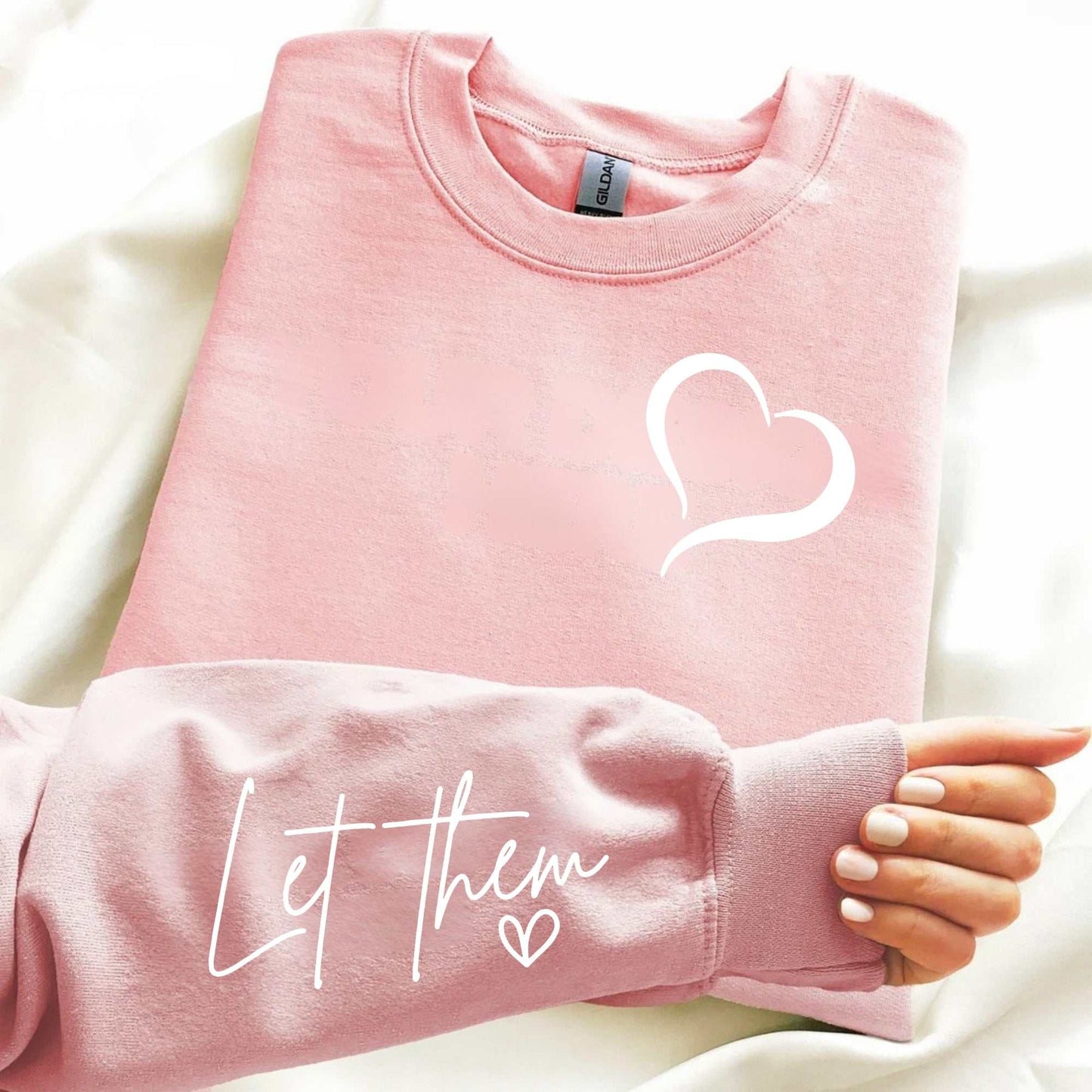 Pink embroidered sweatshirt with heart detail and "Let Them" affirmation on the sleeve, promoting self-love and emotional wellness.