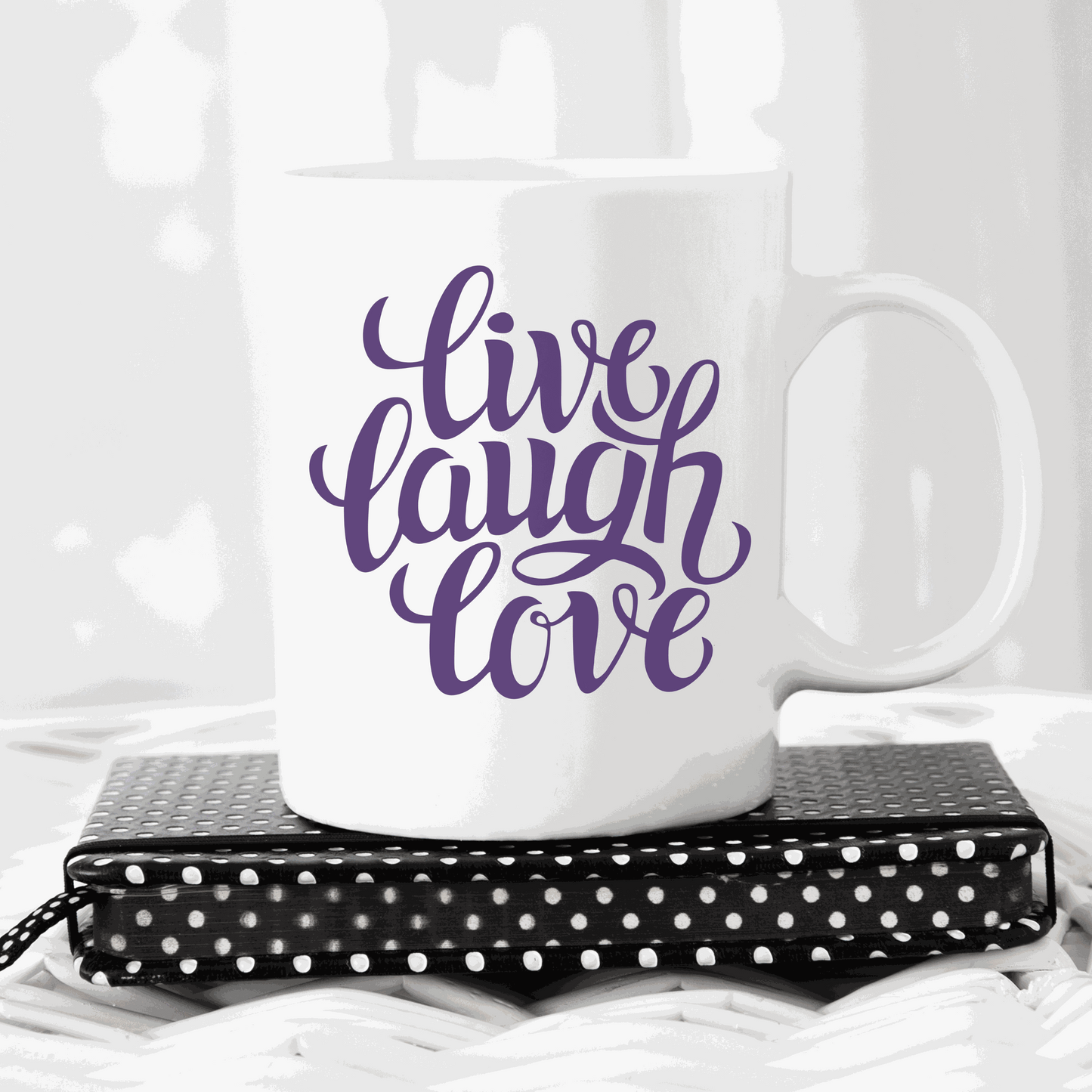 White ceramic mug with "Live, Laugh, Love" text in purple script font.