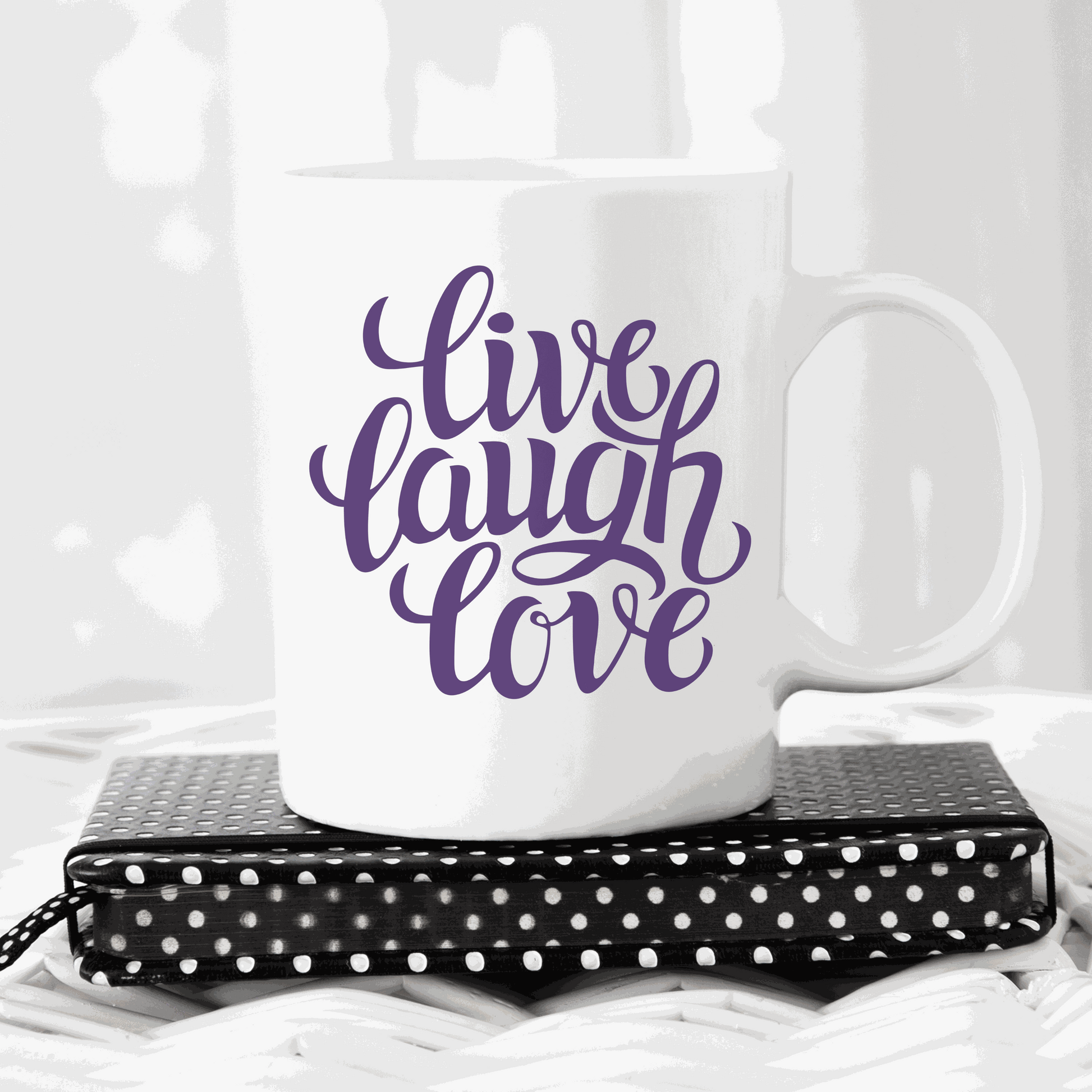 White ceramic mug with "Live, Laugh, Love" text in purple script font.