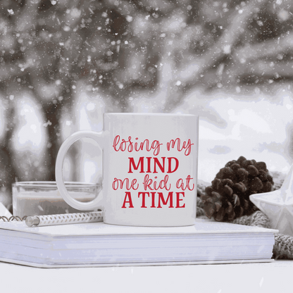 White ceramic mug with humorous "Losing my Mind one Kid at a Time" design.