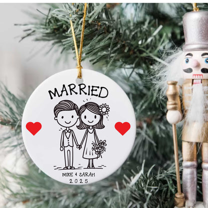 Personalized first Christmas married gift ornament with custom names and date, featuring a cute bride and groom illustration on a round porcelain bauble with gold hanging string.