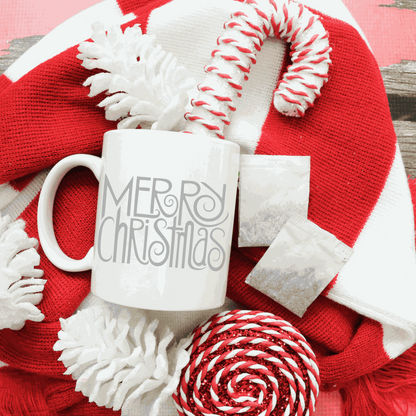 Merry Christmas white ceramic mug with festive candy canes and red scarf background.