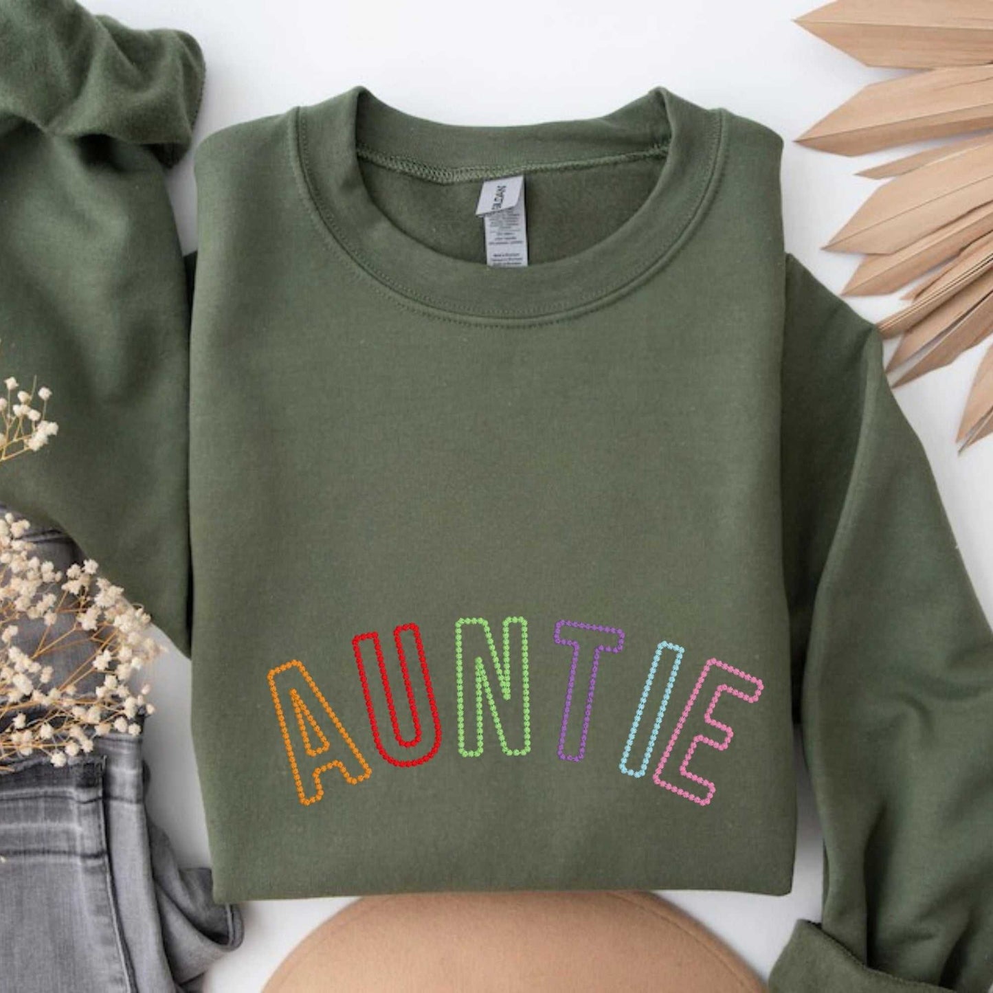 Olive green sweatshirt with embroidered rainbow letters spelling AUNTIE, cozy cotton blend fabric, unisex fit, ribbed neckline and cuffs.