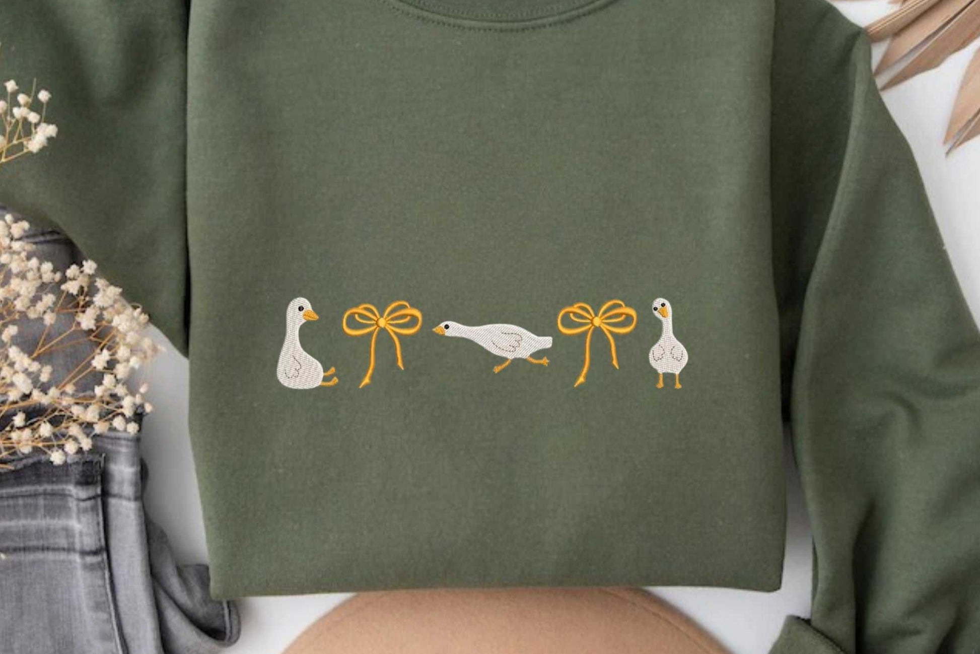 Olive green sweatshirt with embroidered geese and orange bows.