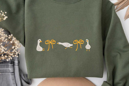 Olive green sweatshirt with embroidered geese and orange bows.