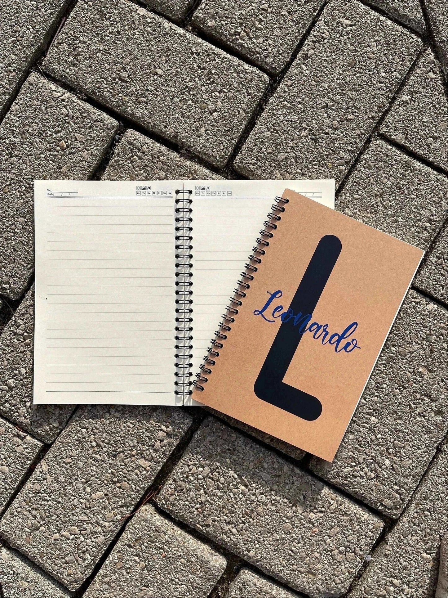 Personalized soft cover spiral notebook with kraft cover, 8 x 5.5 inches, open on a stone surface.